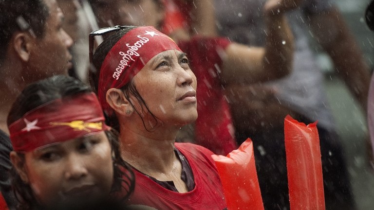 Supporters of Myanmar opposition leader Aung San Suu Kyi brave the rain as they celebrate after hearing the first official results of the elections (AFP PHOTO / Nicolas ASFOURI).