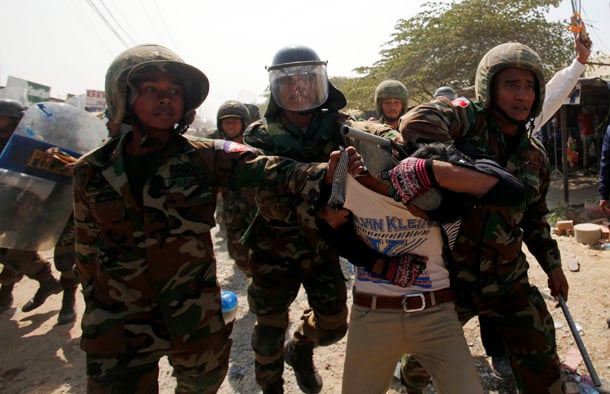 Worker who had been taking part in a protest is escorted by Cambodian soldiers after clashes broke out, on the outskirts of Phnom Penh