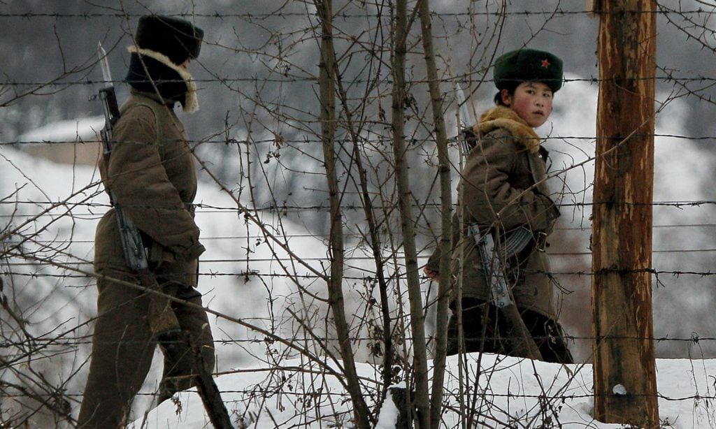 A North Korean female soldier, right, looks back as she and another patrol on a pathway along the bank of the Yalu River, the China-North Korea border river, near North Korea's town of Sinuiju, opposite to the Chinese border city of Dandong, Sunday Nov. 28, 2010. (AP Photo/Andy Wong)