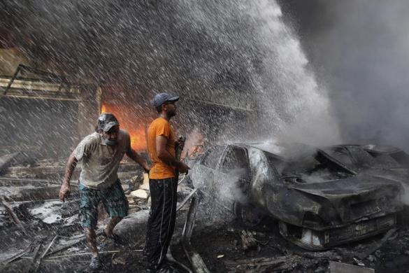 Supporters of Hezbollah try to extinguish the fire from burning cars at the site of a car bomb in Beirut's southern suburbs, August 15, 2013.  REUTERS/Hasan Shaaban