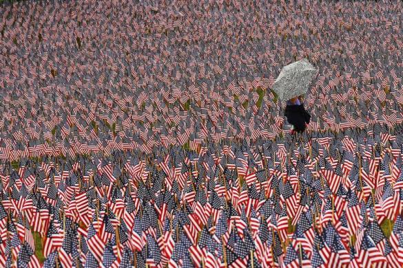 A pedestrian carrying an umbrella walks through a Memorial Day display of United States flags on the Boston Common in Boston, Massachusetts May 23, 2013. According to the Massachusetts Military Heroes Fund, the flags are planted on the Common for fallen Massachusetts service members at the Memorial Day holiday, which will be celebrated May 27 in the U.S.  REUTERS/Brian Snyder