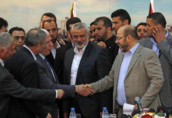Palestinian Fatah delegation chief Azzam al-Ahmed (center-left) shakes hands with Hamas deputy leader Musa Abu Marzuk (right) in the presence of Hamas Prime Minister in the Gaza Strip Ismail Haniyeh (center), after signing a reconciliation agreement in Gaza on April 23, 2014. Photo by said Khatib/AFP/Getty Images