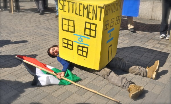 A protester depicts the impact of illegal Israeli settlements on Palestinians.